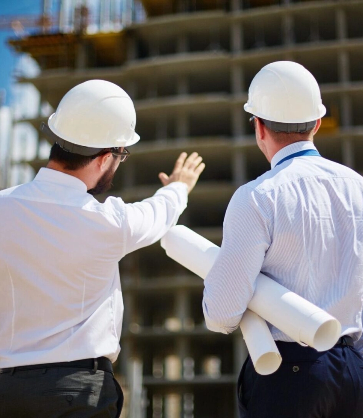 Two men in hard hats looking at a building